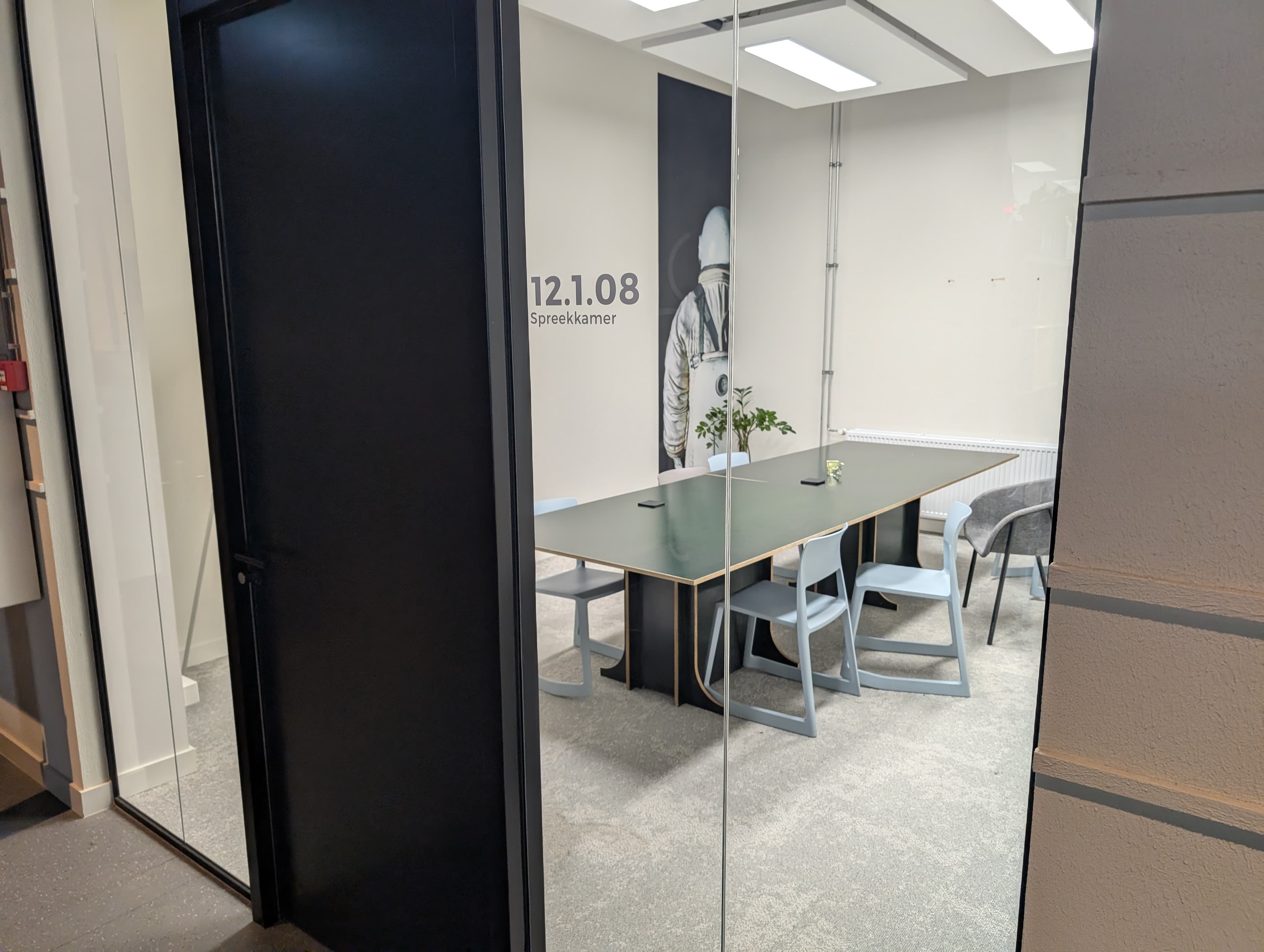 Vergadertafel en lichte stoelen in de kamer tegenover de pantry